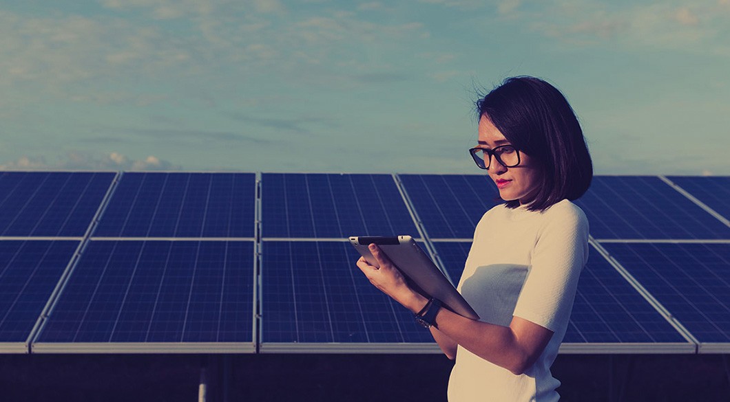 woman standing in front of solar panels and looking at iPad